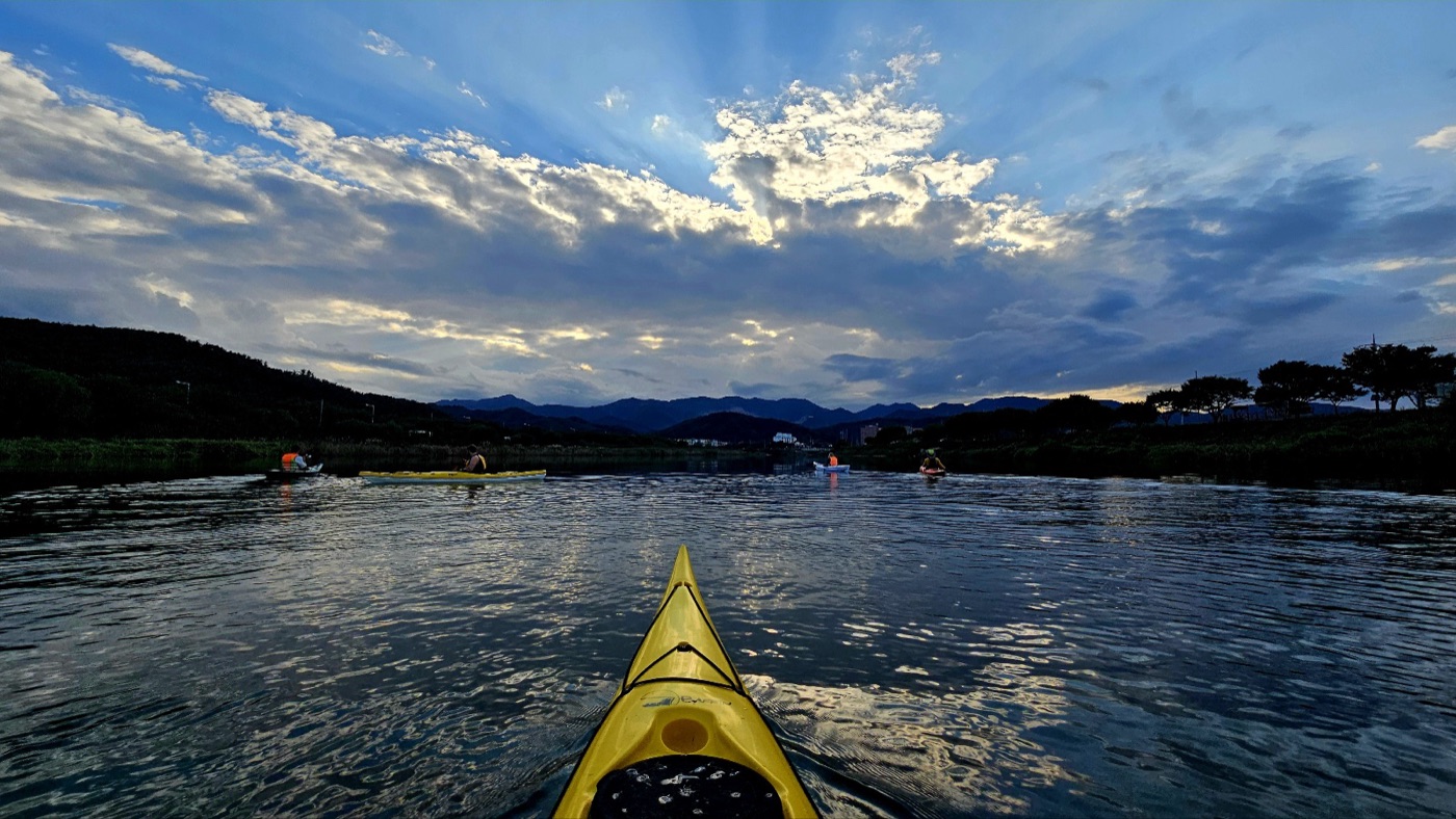 The bow of a kayak on the river at dusk