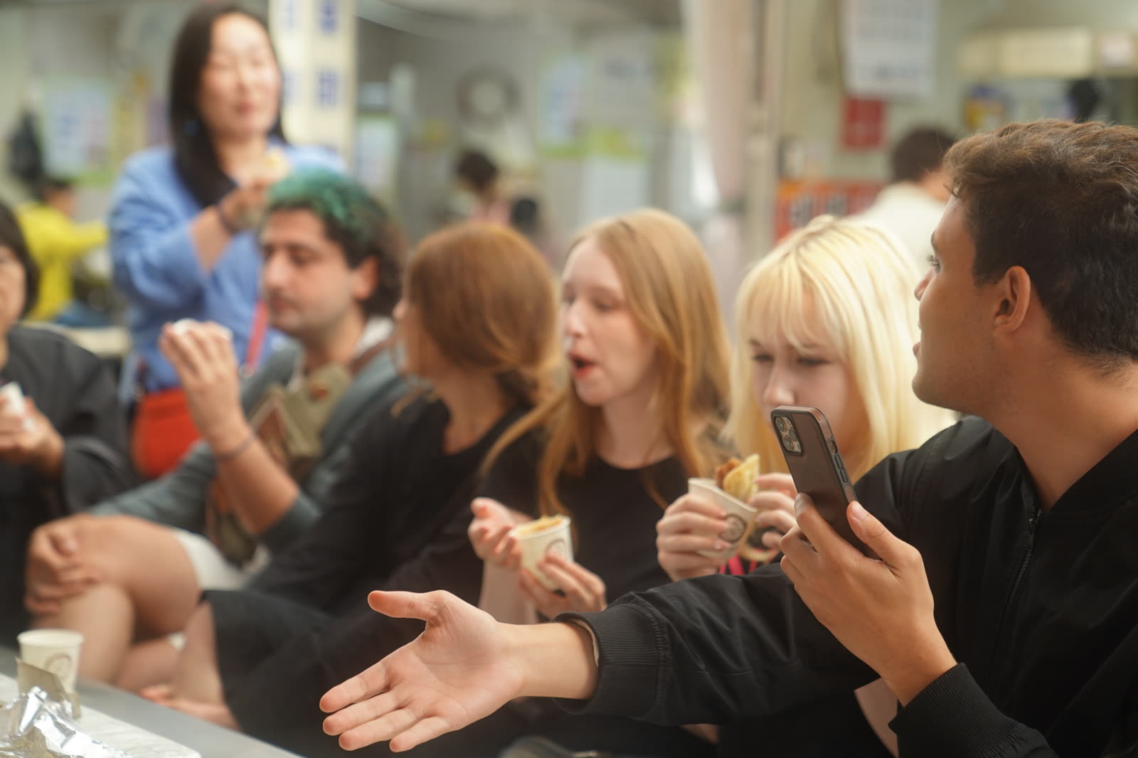 Guests laughing over food at a market stall