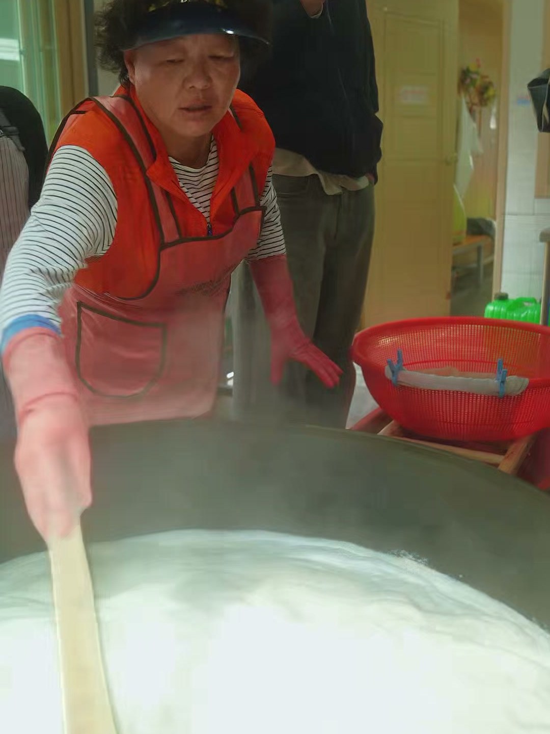The dubu maker stirring soy milk in an iron cauldron